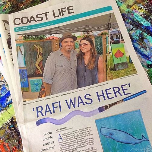 A local couple poses with their artwork at a market, featured in a newspaper article titled 'Coast Life'. A headline reading 'RAFI WAS HERE' is prominently displayed, along with images of paintings in the background.