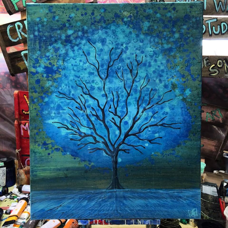 A painting of a solitary tree with bare branches, set against a blue and green textured background. The artwork emphasizes different shades of blue, creating a calming and serene atmosphere.