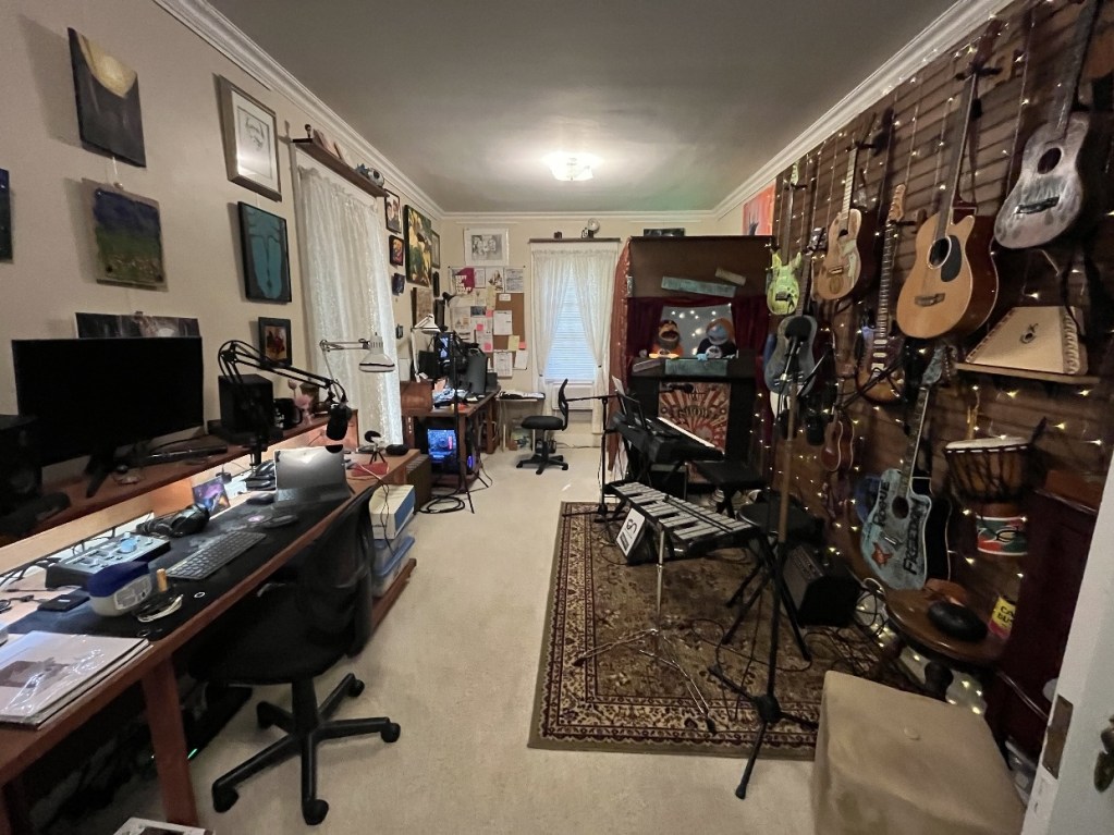 A creative workspace filled with musical instruments, artwork, and recording equipment, showcasing a vibrant artistic environment.