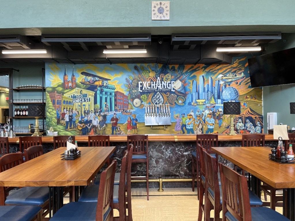 A vibrant mural at The Exchange in Oil City, featuring scenes of local history, the building at 100 Seneca Street, and diverse portraits of community members.