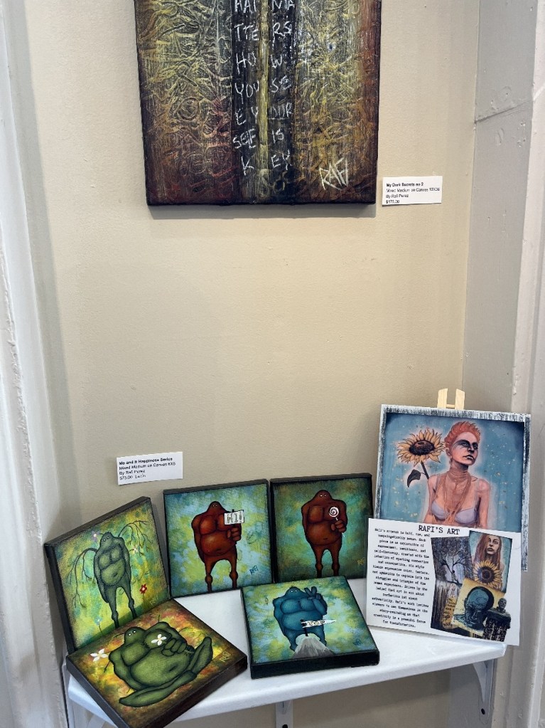 An art display featuring various colorful paintings and sculptures at the Red Brick Gallery in Foxburg, PA, showcasing a blend of styles and mediums.
