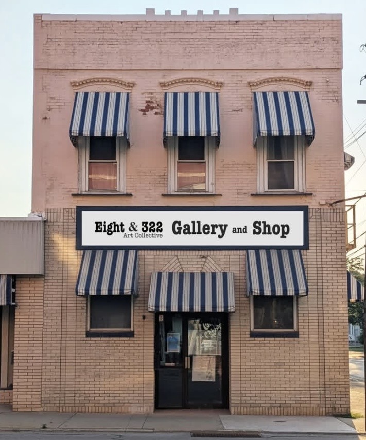 Exterior view of the Eight & 322 Gallery and Shop featuring a pink building with striped awnings and a large sign displaying the gallery's name.