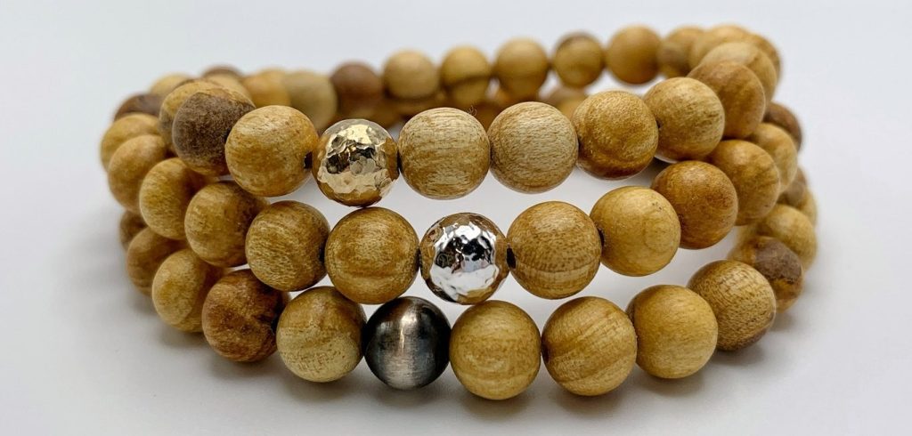 Three strands of wooden bead bracelets with gold and silver accent beads.